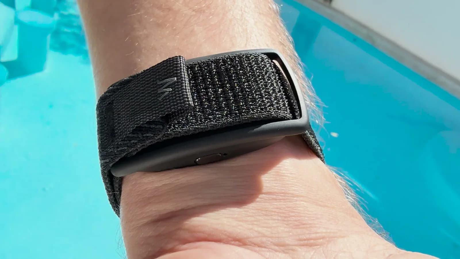 Close-up of the Memoket Gem AI note taker in its black woven wristband on a wrist