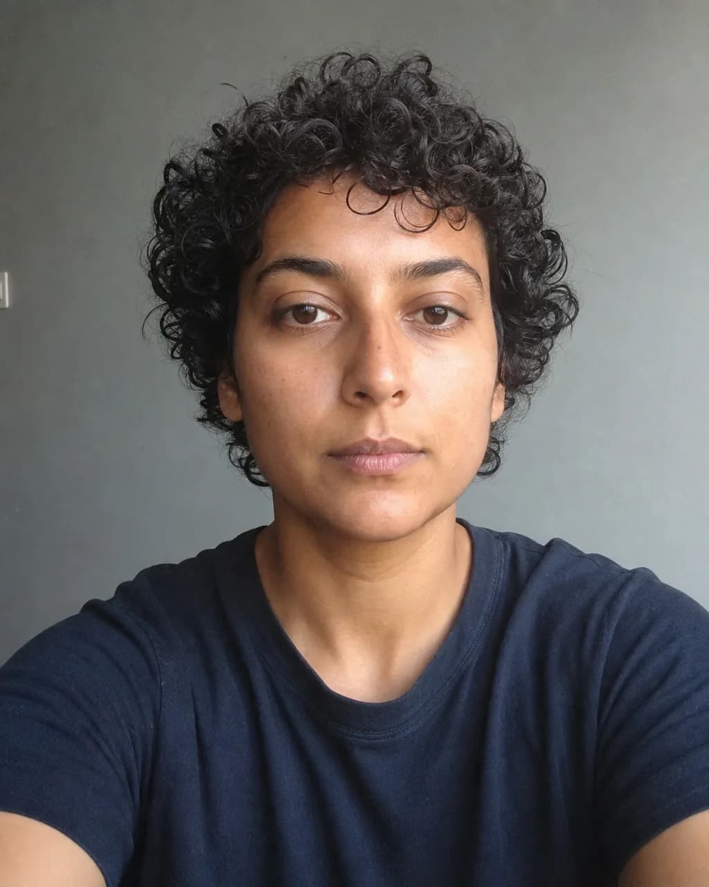 Fictional person with short natural curls before a haircut preview